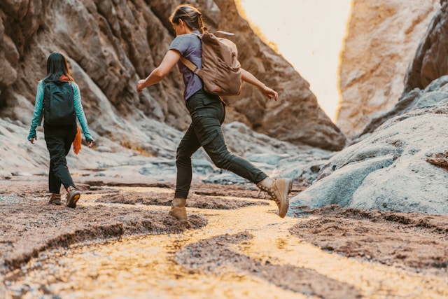 Two women hiking, one woman is making big strides, representing personal growth
